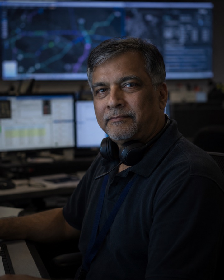 Portrait of a dispatcher with a headset around his neck in a dim operations control room