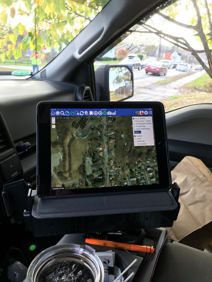 Atlas on a truck-mounted tablet showing the network over aerial imagery, crew working outside