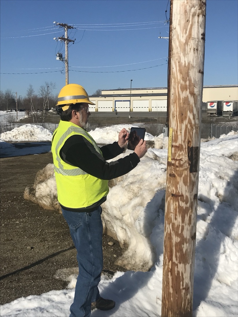 A field technician capturing pole data on a handheld device in the field