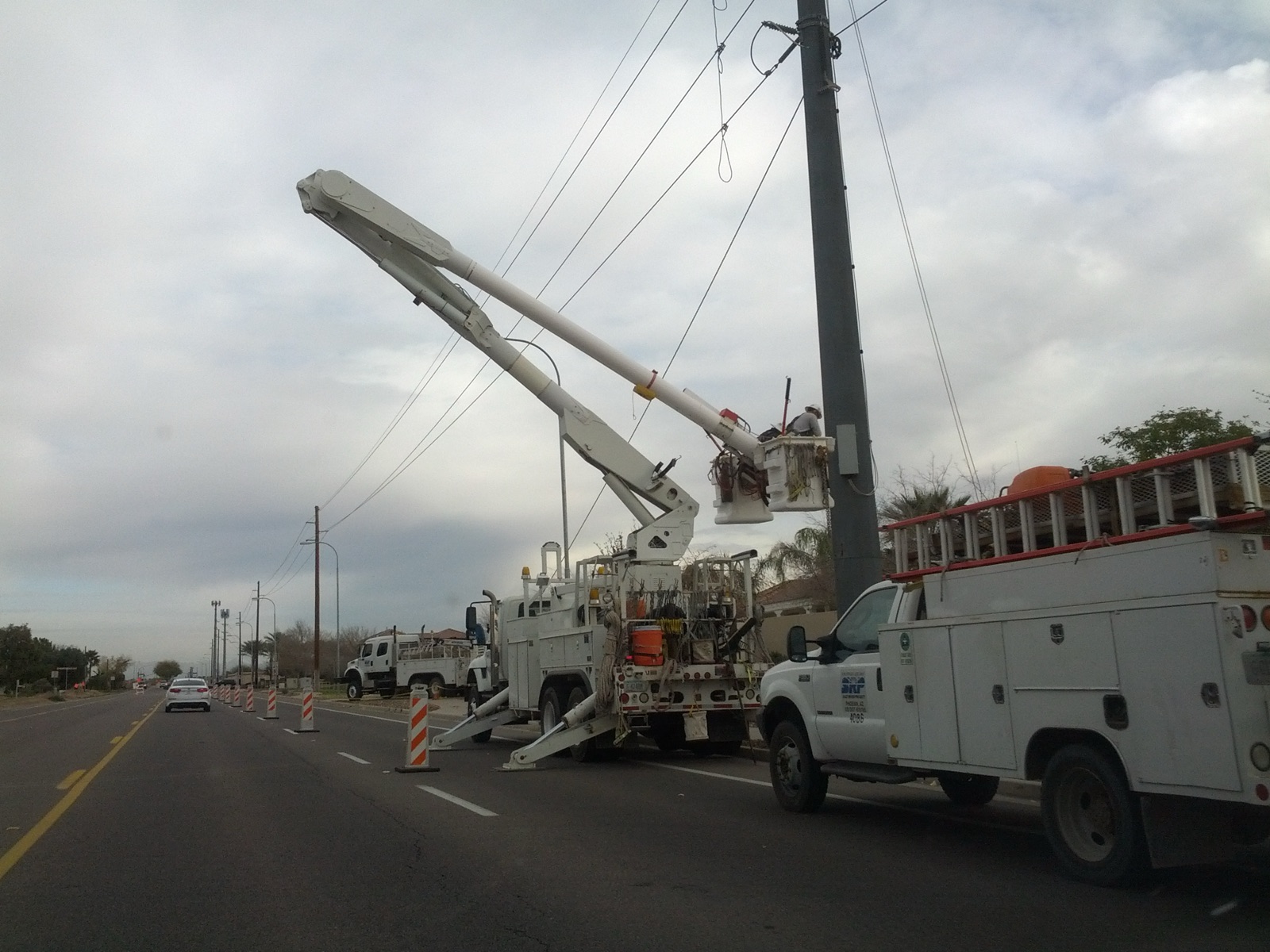 Utility crews in bucket trucks working a distribution pole in the Arizona desert