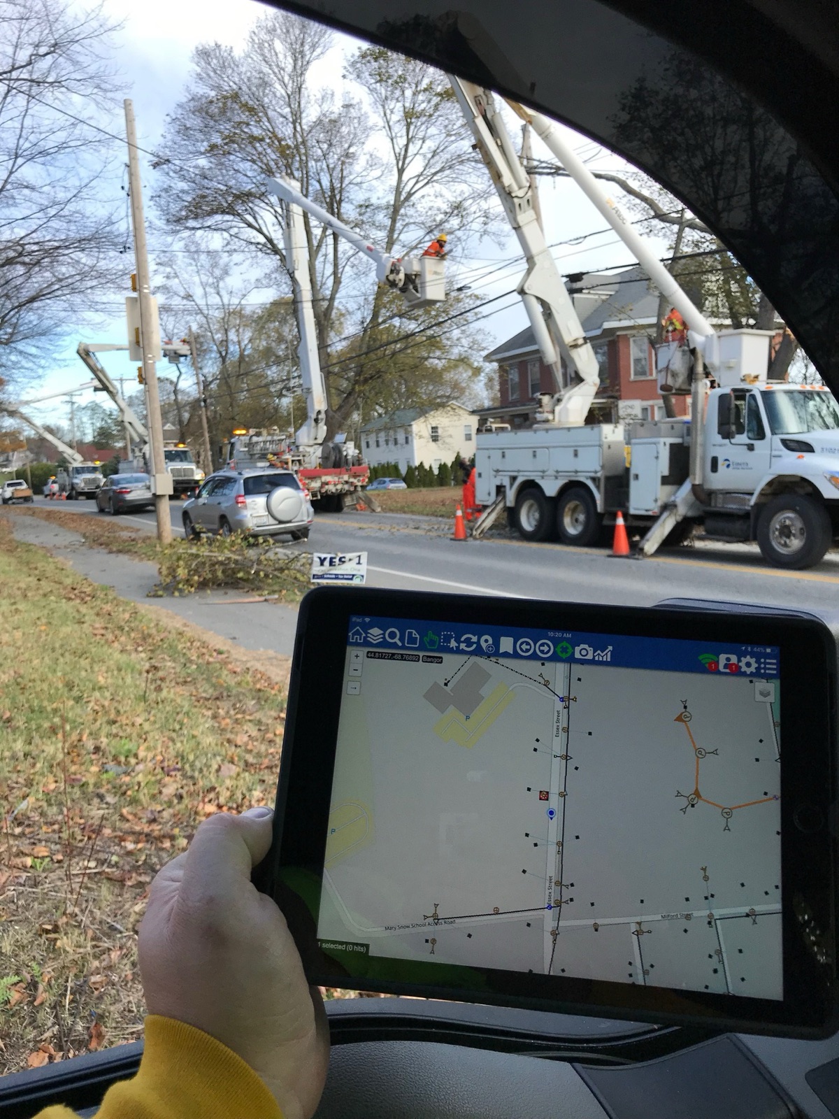 Storm restoration in Maine: a line of bucket trucks working tree-damaged lines along a residential street